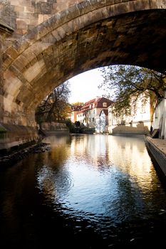 A large stone bridge detail along a river going through the old town area of Prague, Czech Republic.