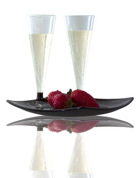 Two glasses of spumante and some strawberries on black plate