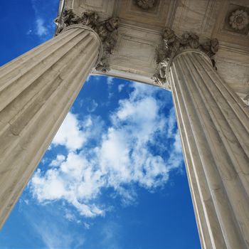 Low angle view looking up at blue sky with clouds and columns of Supreme Court building in Washington DC.