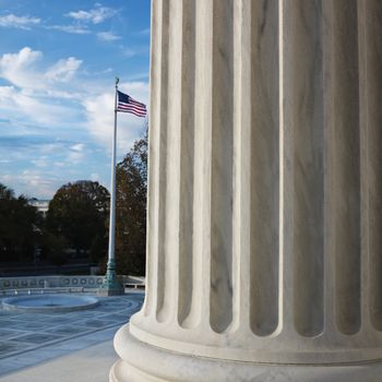 Column of Supreme Court building with American flag in Washington DC, USA.