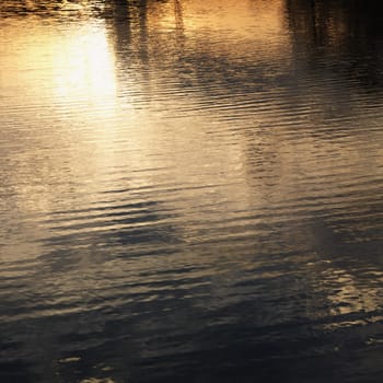 Reflections of orange and yellow sunset on water.