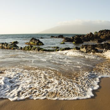 Landscape of waves lapping on rocky beach.