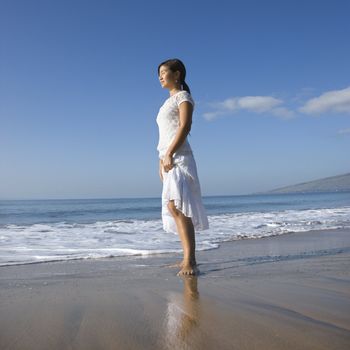 Young Asian female standing at shoreline.