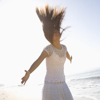 Young adult Asian female with arms outward and throwing hair back.