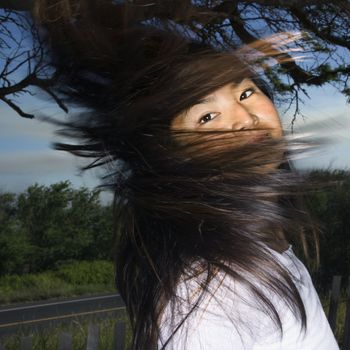 Young adult Asian female looking at viewer and swinging her hair.