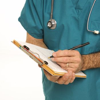 Mid-adult Caucasian male doctor in scrubs making notes on a patient's chart.