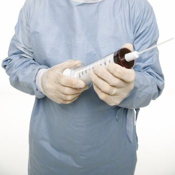 Mid-adult Caucasian male wearing scrubs and holding an oversized syringe.