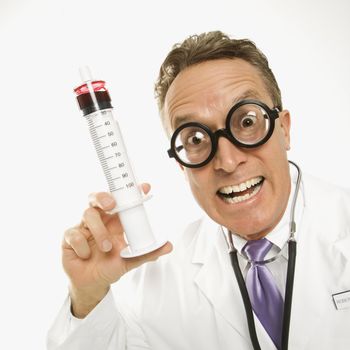 Mid-adult Caucasian male doctor wearing eyeglasses holding an oversized syringe.