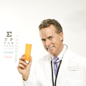 Mid-adult Caucasian male doctor holding a medical pill bottle with an eye chart in the background.