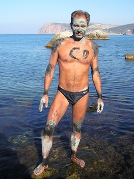 man was smeared by useful therapeutic mud on the shore of Azov sea in order to obtain therapeutic effect. Mud gradually dries in the sun, and it then washes off by water.