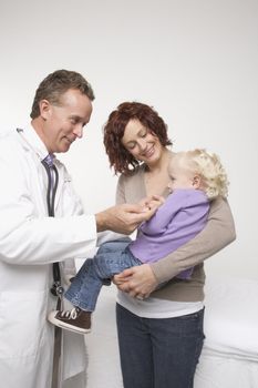 Middle-aged adult Caucasian male doctor comforting Caucasian female toddler.