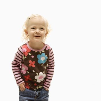 Young Caucasian female toddler with hands in her pockets and laughing.