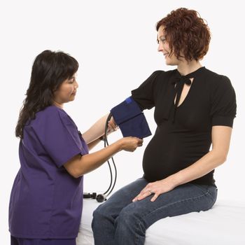 Pregnant Caucasian mid-adult woman having blood pressure checked by nurse.