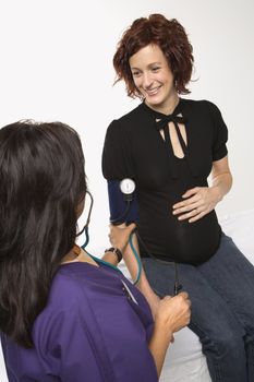 Pregnant Caucasian mid-adult woman having vital signs checked by nurse.