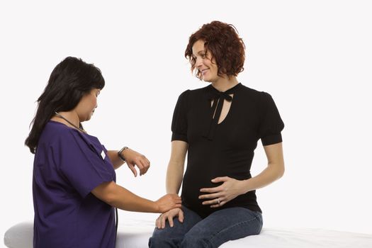 Pregnant Caucasian mid-adult woman having vital signs checked by nurse.