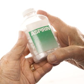 Close-up of elderly male Caucasion hands holding aspirin bottle.