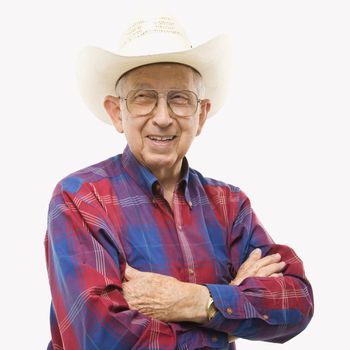 Portrait of smiling Caucasion elderly man wearing plaid shirt and cowboy hat with arms crossed.