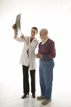 Mid-adult Caucasian female doctor showing x-ray to elderly Caucasian male in neck brace.