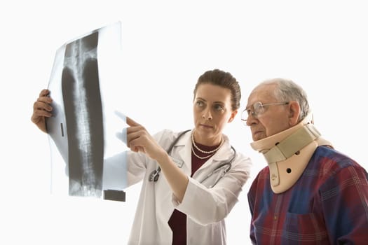 Mid-adult Caucasian female doctor ponting at x-ray with elderly Caucasian male in neck brace looks on.