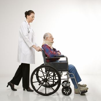 Mid-adult Caucasian female doctor pushing elderly Caucasian male with neck brace in wheelchair.