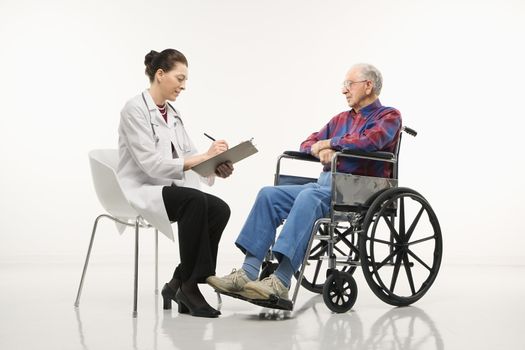 Mid-adult Caucasian female doctor taking notes with an elderly Caucasian male in wheelchair to her side.