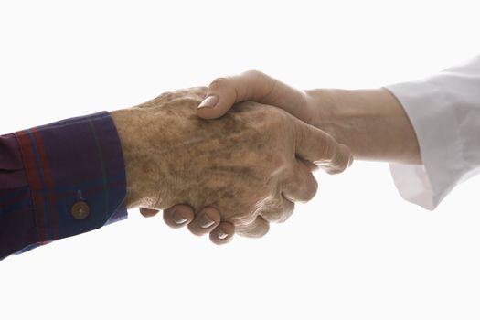 Close-up of elderly Caucasian male shaking hands with mid-adult Caucasian female hand.