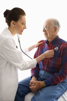 Mid-adult Caucasian female doctor listening to elderly Caucasian male's heart with stethoscope.
