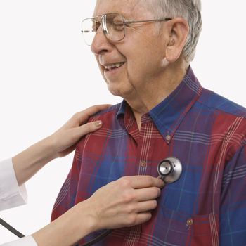 Mid-adult Caucasian female hands listening to elderly Caucasian male's heart with stethoscope.