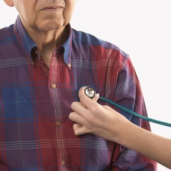 Mid-adult Caucasian female hand with stethoscope at elderly Caucasian male's chest.