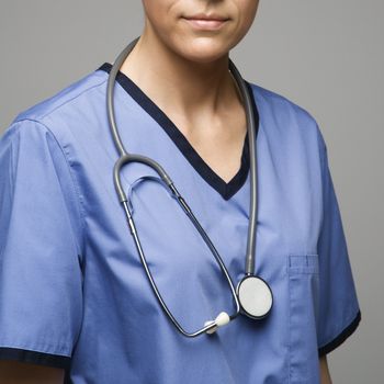 Close-up view of Caucasian woman doctor wearing scrubs with stethoscope around neck.