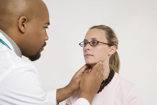 Mid-adult African-American doctor examining Caucasion mid-adult female patient.