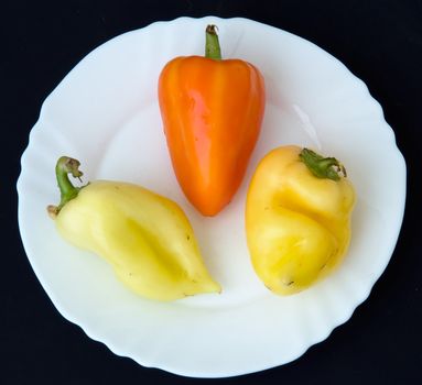 sweet pepper on a white plate on a black background