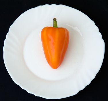 the sweet pepper on a white plate on a black background