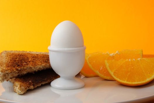 boiled egg, orange and bread as breakfast