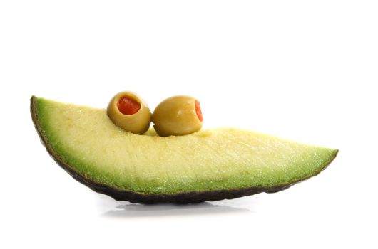 piece of avocado and two green olives, white background