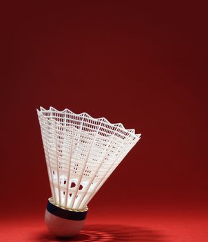 nylon badminton shuttlecock with its shadow, red background