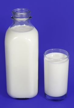 bottle and glass filled with fresh milk, blue background