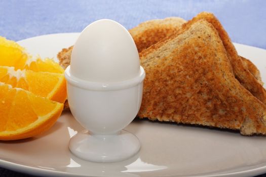 boiled egg, orange and bread as breakfast