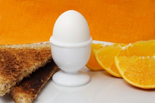 boiled egg, orange and bread as breakfast