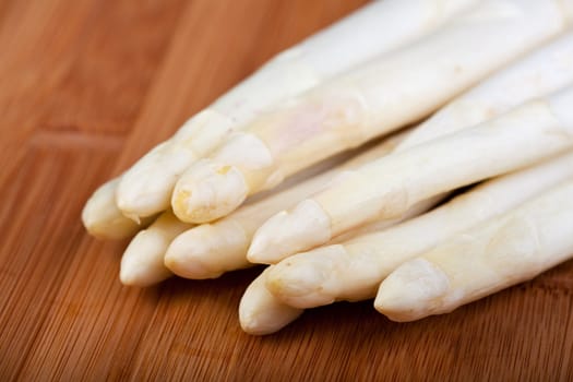 raw white asparagus on a wooden blank