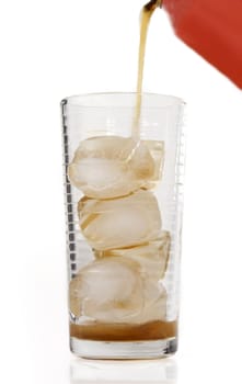 pouring cola in a glass with ice cubes