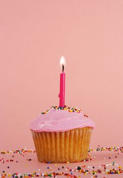 homemade cupcakes with pink icing and candle