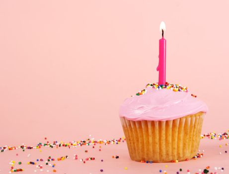 homemade cupcakes with pink icing and candle