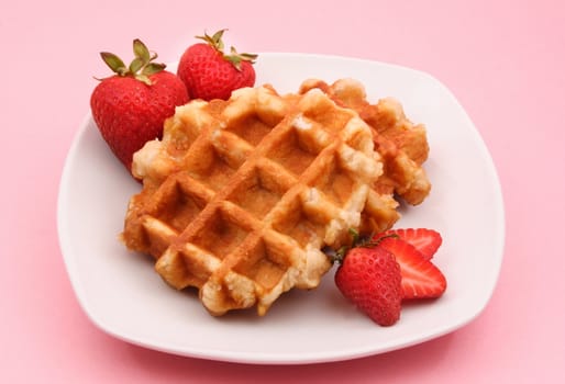 belgian waffles and strawberries in white plate, pink background