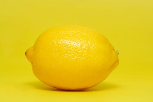 Whole fresh lemon on yellow background