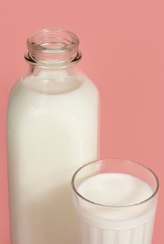 bottle and glass of milk on pink background