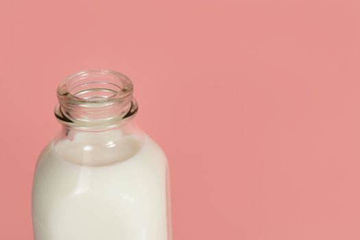 closeup on a glass bottle full of milk, on pink background