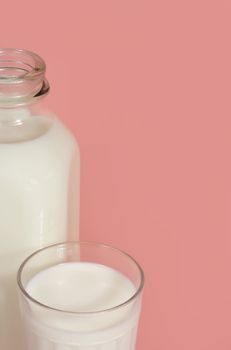bottle and glass of milk on pink background