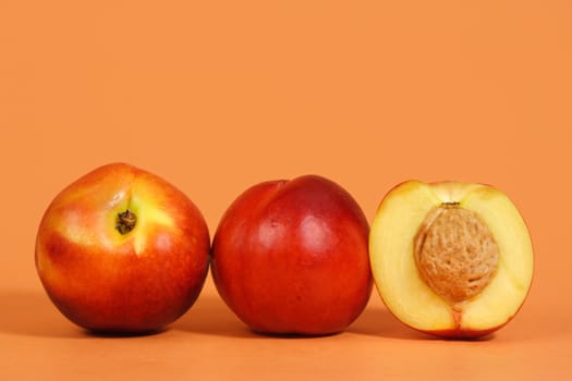 three nectarines with peach background