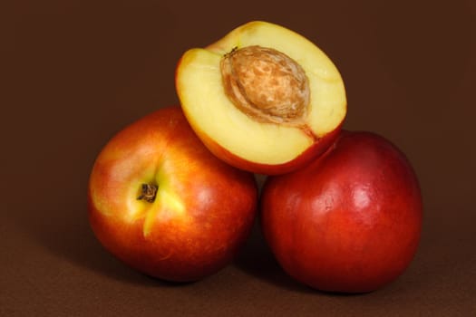 three nectarines on brown background